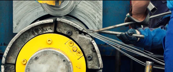 Arbetstagare som håller en metallstav mot en tillverkningsmaskin för skärning / avskärning av stålplåt — Stockfoto