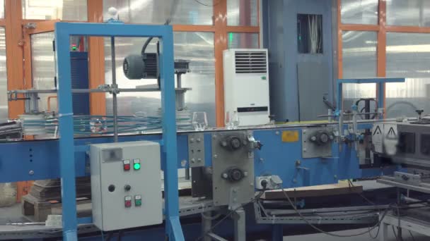 Línea transportadora automática o cinta con filas de vasos de cristal transparentes en fábrica industrial . — Vídeos de Stock