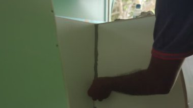 Limandaki bir balıkçı teknesinin ahşap parçalarını tamir eden genç adamın ellerini kapatın..