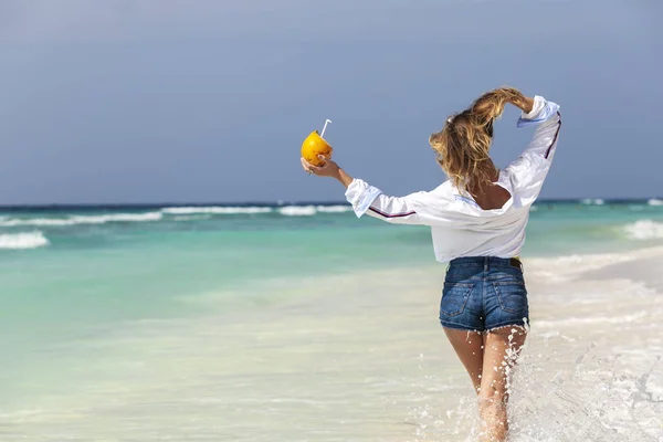Blonde girl in denim shorts with fresh coconut — Stock Photo, Image