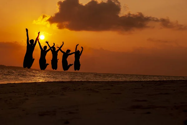 Groep gelukkige jonge meisjes springen in de beach op mooie zomerse zonsondergang. Stockfoto