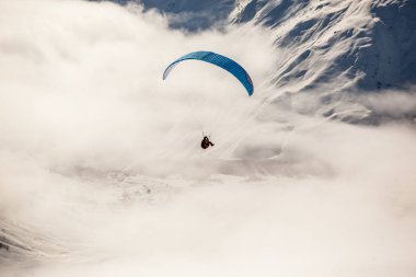 Karlı dağlarda bulutlarla paraşütle atlamak
