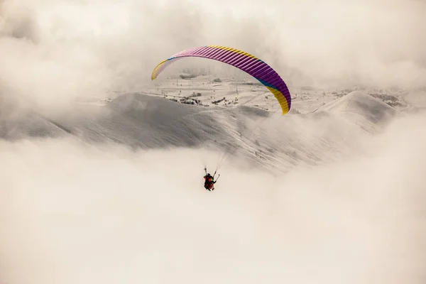 Gleitschirmfliegen in den verschneiten Bergen mit Wolken — Stockfoto