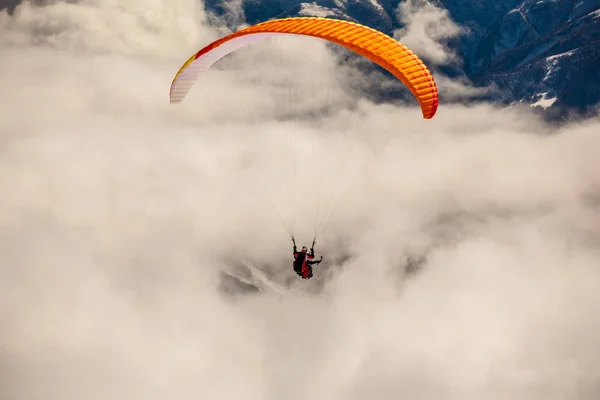 Paragliden in de besneeuwde bergen met wolken — Stockfoto