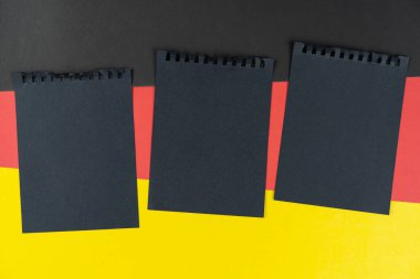 Blacklist Germany. black sheet of notebook lies on German flag. Mock up, copy space, pattern, cardboard texture.