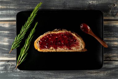 Reçelli çavdar ekmeği ve biberiye. Tahta kaşık. Kahvaltı..