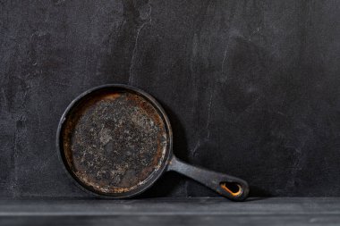 Siyah beton arka planda demir kızartma tavası. Boşluğu kopyala.