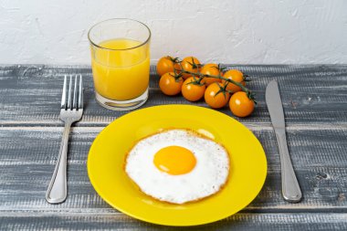 fried egg on yellow plate with cherry tomatoes and orange juice. Light breakfast.