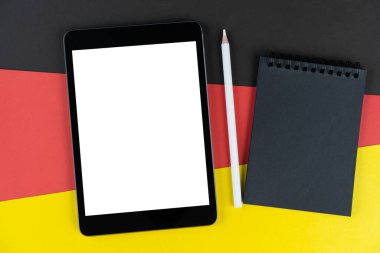 Almanya bayrağında siyah tablet, e-kitap, defter ve beyaz kalem var. Doku Alman ulusal bayrağı renkli karton. Model yap, boşluğu kopyala, düzenle.