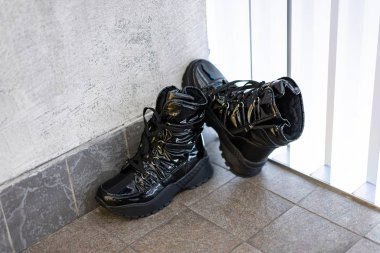  black all-season boots, patent leather stand on floor of mall. Great location, very effective photo for advertising a shoe store clipart