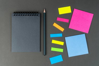 Siyah defter, çok renkli notlar ve siyah arka planda kalem. Model yap, kopyala uzayı. düşünceler, fikirler.