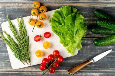 Biberiye, salatalık, salatalık ve beyaz kesim tahtasındaki kiraz domatesleri. Salata için sebze hazırla.