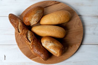 Buğday, çavdar ve çoklu tahıllı baget. Tahta kesme tahtasındaki farklı ekmek.