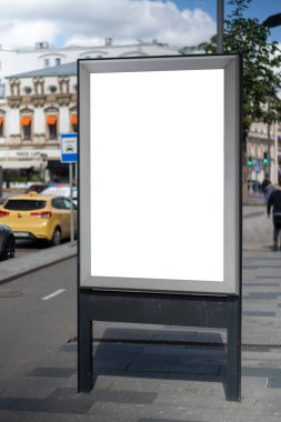Şehirde dikdörtgen şeklinde dikey ışık kutusu yap. İnşaat reklamı. Uzayı kopyala Dar sokaktaki reklam panosu. Arkaplan inşaatına ve karayoluna karşı.