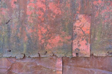 old iron wall consisting of separate pieces of metal. metal patches. Metal sheets from which the area is paint. Iron rusting.