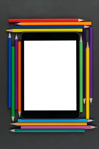 tablet in frame multicolored pencils on black background, mock up, copy space
