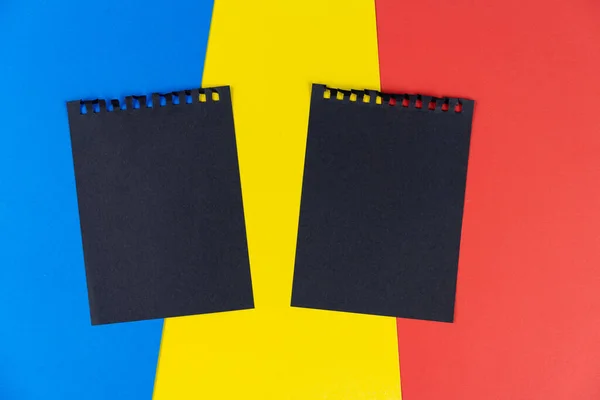 Black list Romania. Mourning, ban, sanctions, politics. black sheet of notebook lies on Romanian flag. Mock up, copy space, pattern, cardboard texture.