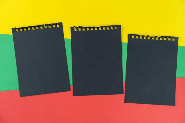 Black list Lithuania. Mourning, ban, sanctions. black sheets of notepad is on Lithuanian flag. Mock up, copy space, pattern, cardboard texture.