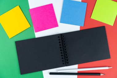 çok renkli notlar, siyah defter ve İtalyan bayrağında iki kalem. Model, kopyalama alanı, desen, karton doku. İtalyan tatil konsepti, eğlence listesi