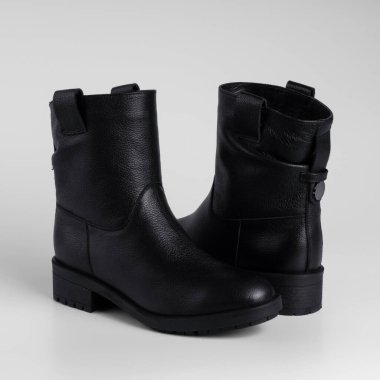 black female leather ankle boots demi season flat shoes for catalog on a white background with shadows, close-up