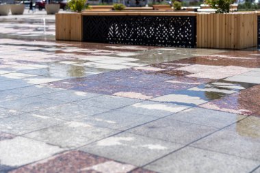 Yağmurdan sonra ıslak kaldırım. Mermer kaldırımda yağmur üstüne su birikintileri. Yağmurdan sonra bir meydanda su birikintileri.