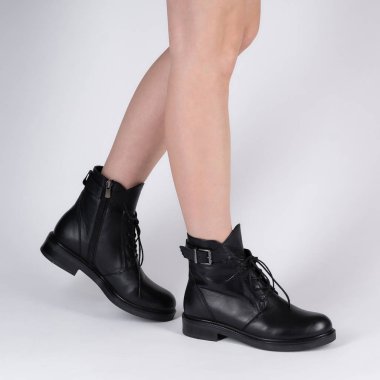 demi seasonal female black leather shoes with lacing on model legs shot in studio on a white background. Beautiful stylish pair of shoes for catalog