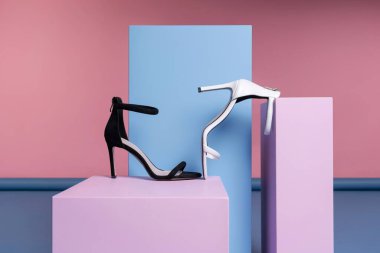 Stüdyodaki pembe, mavi bir standın üzerinde topuklu kadın ayakkabıları var. Tanıtım fotoğrafı.