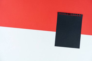 Blacklist Monaco. Mourning, ban, sanctions, politics. black sheet of notebook lies on Monaco flag. Mock up, copy space, pattern, cardboard texture.