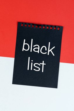 Blacklist Monaco. Mourning, ban, sanctions, politics. black sheet of notebook lies on Monaco flag. Mock up, copy space, pattern, cardboard texture.