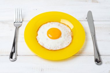 Sarı tabakta kızarmış yumurta. Çatal ve bıçak. Kahvaltı..