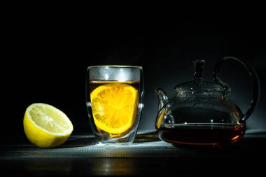 Şeffaf termik bardakta limonlu taze siyah çay. Cam çaydanlık. Çay töreni.