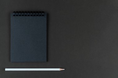 Siyah arka planda siyah defter ve beyaz kalem. Kağıt arkaplanda duran siyah kağıt ve beyaz kalemi taklit et. Boşluğu kopyala.