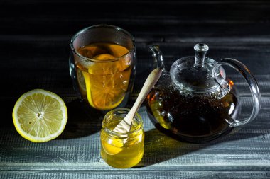 Bal, limon ve siyah çay siyah ahşap masada termostatta. Çay töreni. 