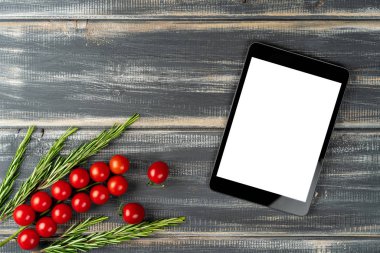 Çeri domatesleri ve tablet bilgisayarı ahşap masanın üzerinde. Salata tarifi, vejetaryen menüsü.