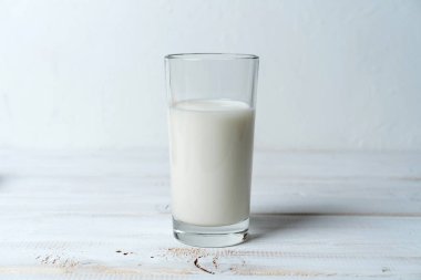 Tarif veya ürün bileşimi için beyaz ahşap masa üzerindeki bir bardak süt kopyalama alanı
