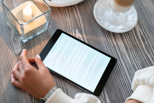 Kahvaltıda kafede e-kitap okuyan bir kız. Samimi bir restoranın masasındaki tablet bilgisayardan gelen metni oku. Çekiş okuma bilgisi