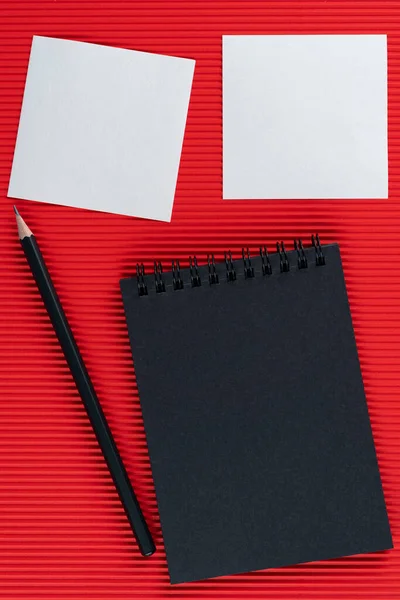 Černý Zápisník Tužka Dva Bílé Tóny Červeném Vlnitém Lepenkovém Pozadí — Stock fotografie