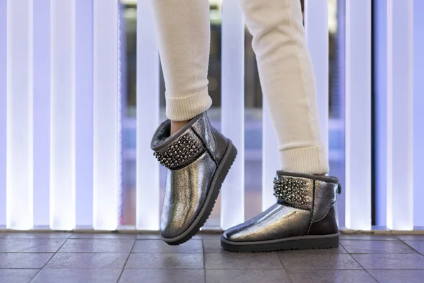 İç modelinde yapay elmasları olan güzel gümüş ugg dişileri. Yan görüş. Ayakkabı mağazası. 