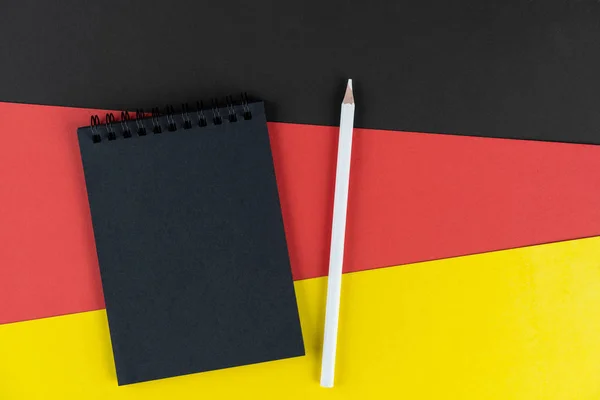 黑名单德国 黑色笔记本和白色铅笔挂在德国国旗上 复制空间 硬纸板质感 — 图库照片
