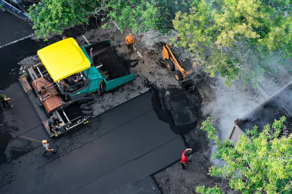 Rusya, Moskova 28 Temmuz 2019 asfalt kaldırım taşı ve yükleyici yolu onarmaya çalışıyor. Yeni asfalt döşeme, üst manzara. İşçiler kaldırım ve yol yüzeyini onarıyor.