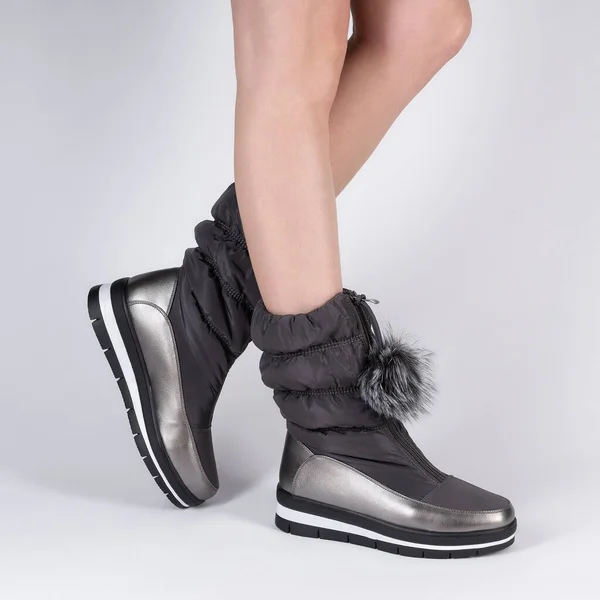 fashionable soft high ankle boots warm winter on a flat low sports sole. Photo on legs of a model on a white background