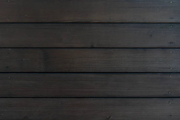 Arkaplan duvarları koyu ahşap tahtalar, vidalara tutturulmuş..