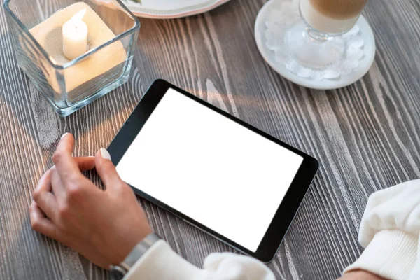 Kafedeki bir masada, kahveli latte ve yanan bir mumun yanında yatar. Masada bir kız oturuyor ve tablete bakıyor. Beyaz perde. Boşluğu kopyala.