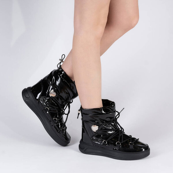 Модные воздушные сапоги согревают зимнюю плоскую спортивную обувь. Фото на ногах модели на белом фоне. Полированная кожа
