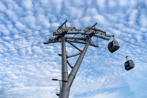 人が行くブースのあるケーブルカー このメカニズムのサポート構造 雲のある青空を背景に — ストック写真