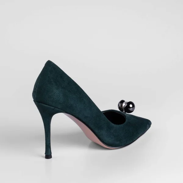 Women green suede high heel shoe with a pearl toe decorative element. Close-up side view studio shot. On a white background for a catalog