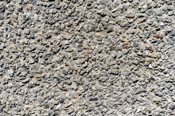 fine gravel road surface. Small stones glued with concrete. Small gravel pavement. Background type view of small rocks on a pavement road.