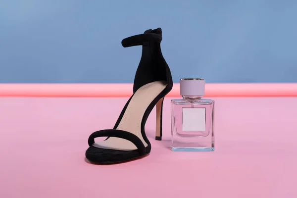 香水瓶 带有空标签的太空矿和女式高跟鞋在一个粉红色的 蓝色的立场上工作室 促销照片 免版税图库照片