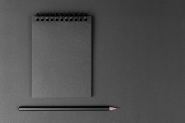 Siyah arka planda siyah defter ve kalem. Kağıt arkaplanda duran siyah kağıt ve siyah kalemi taklit et. Boşluğu kopyala.