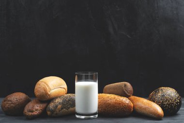 Siyah beton arka planda mini baget ve cam süt. Uzayı kopyala Yemek tarifi. Menü